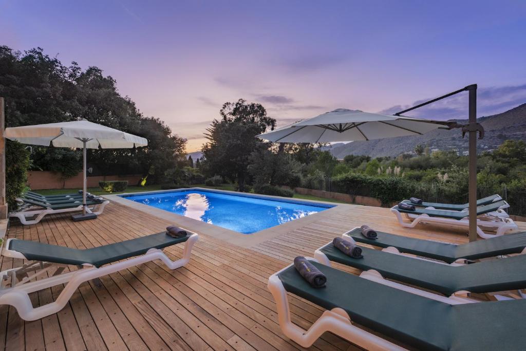 a deck with chairs and umbrellas next to a swimming pool at Villa Coloma in El Port