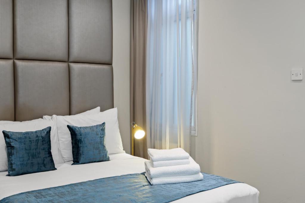 a bedroom with a bed with blue and white pillows at Smart Stay Studio Flat in London