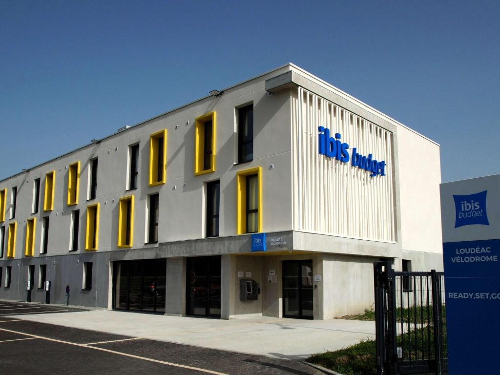 a large white building with yellow windows on it at ibis budget Loudéac Vélodrome in Loudéac