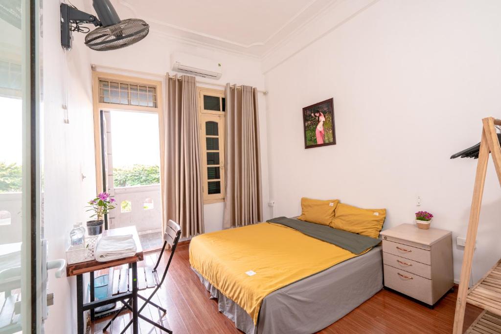 um quarto com uma cama, uma secretária e uma janela em Ha Noi Homestay em Hanói
