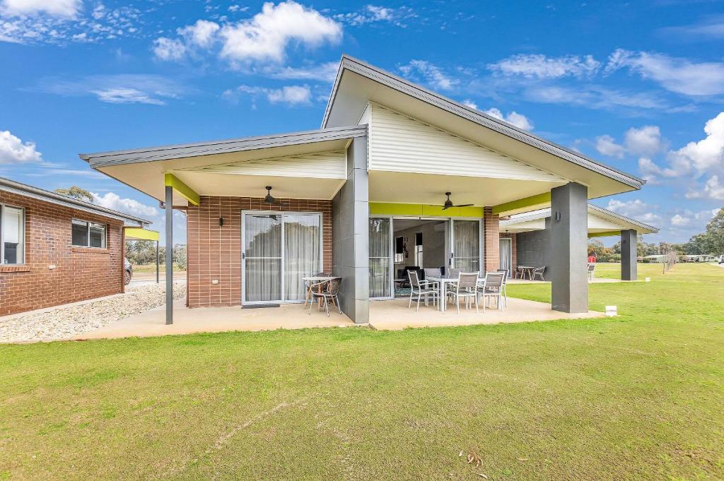 a house with a patio with tables and chairs at Comfort Suites Clubarham Golf Resort in Barham
