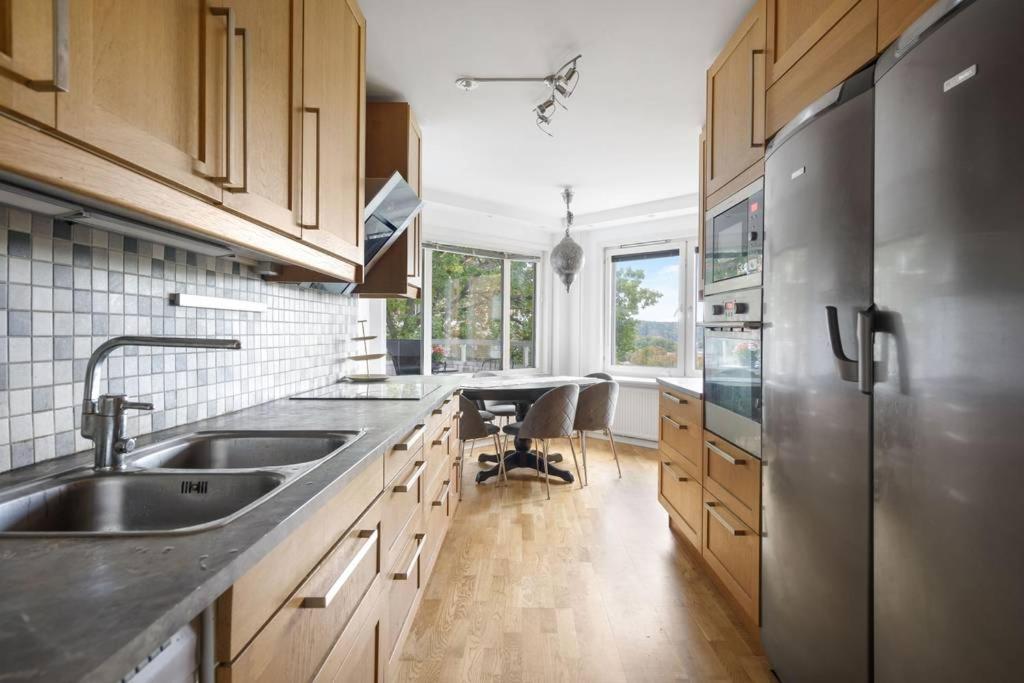 eine Küche mit einem Kühlschrank aus Edelstahl und Holzschränken in der Unterkunft Alby flexible checkin in Stockholm