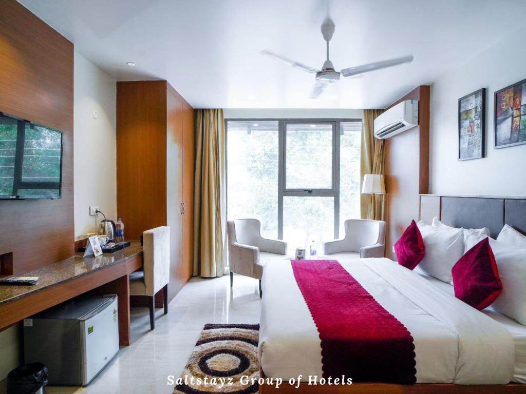 a hotel room with a large bed and a desk at Saltstayz Grand - Unitech Cyber Park in Gurgaon