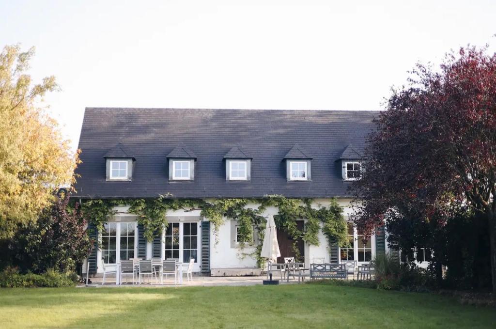 una casa blanca con techo negro y patio en La villa des Crénées, en Héron
