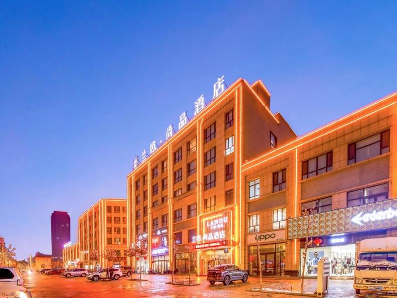 een gebouw op een straat met auto's geparkeerd op een parkeerplaats bij LanOu Hotel Taikoo Li Night Market Kuqa City in Kuqa