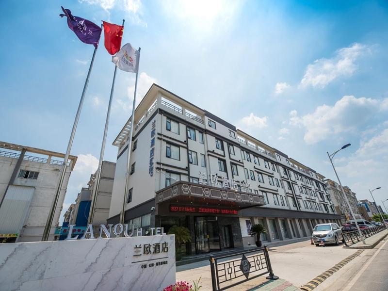 un edificio con dos banderas delante en LanOu Hotel Wuxi Anzhen East High-Speed Railway Station en Wuxi
