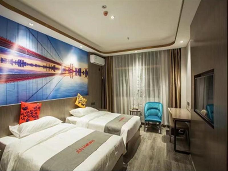 a hotel room with two beds and a painting on the wall at Junyi Hotel Jizhou District East Yangming Road in Ji'an