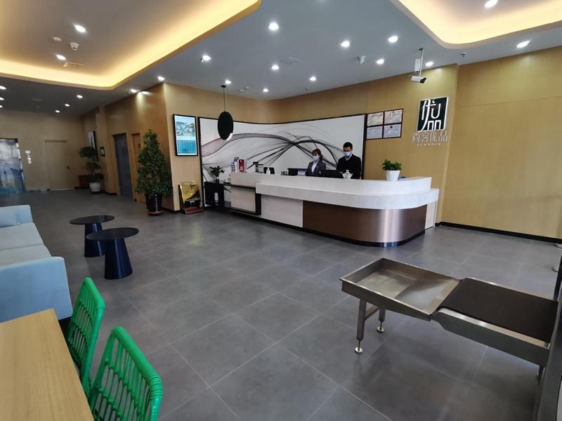 a lobby of a restaurant with a counter and a man at Thank Inn Plus Aksu Kuqa Xingfu Road in Kuqa