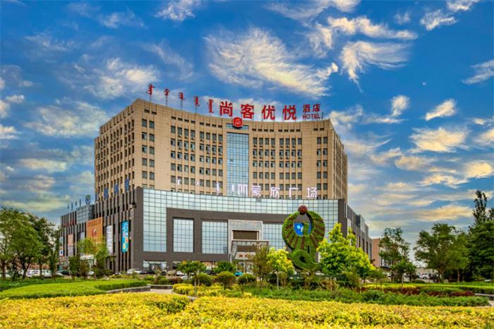 un edificio con un cartel encima en Thank Inn Plus Ordos Qipanjing Government Affairs Service Center, en Shizuishan