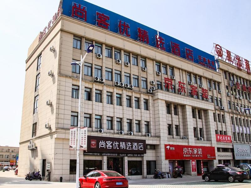 un grand bâtiment avec des voitures garées devant lui dans l'établissement Thank Inn Plus Chuzhou Mingguang Starlight Trade City, à Mingguang