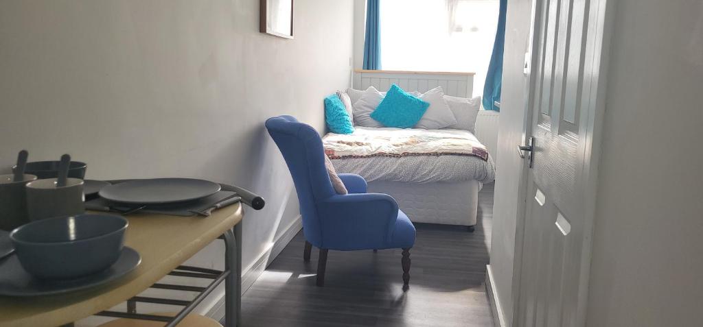 a room with a table and a blue chair and a bed at Stadium Nook in Wembley