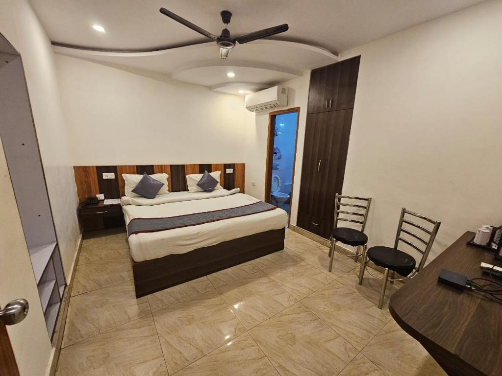 HOTEL ORCHID في لاكناو: غرفة نوم بسرير وطاولة وكراسي