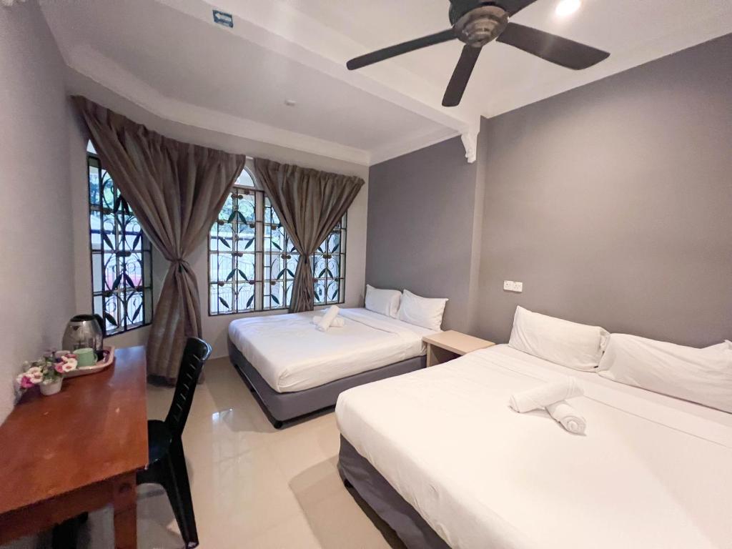 a bedroom with two beds and a desk and a ceiling fan at HUKM CoLiving 1 by Manhattan Group in Kuala Lumpur
