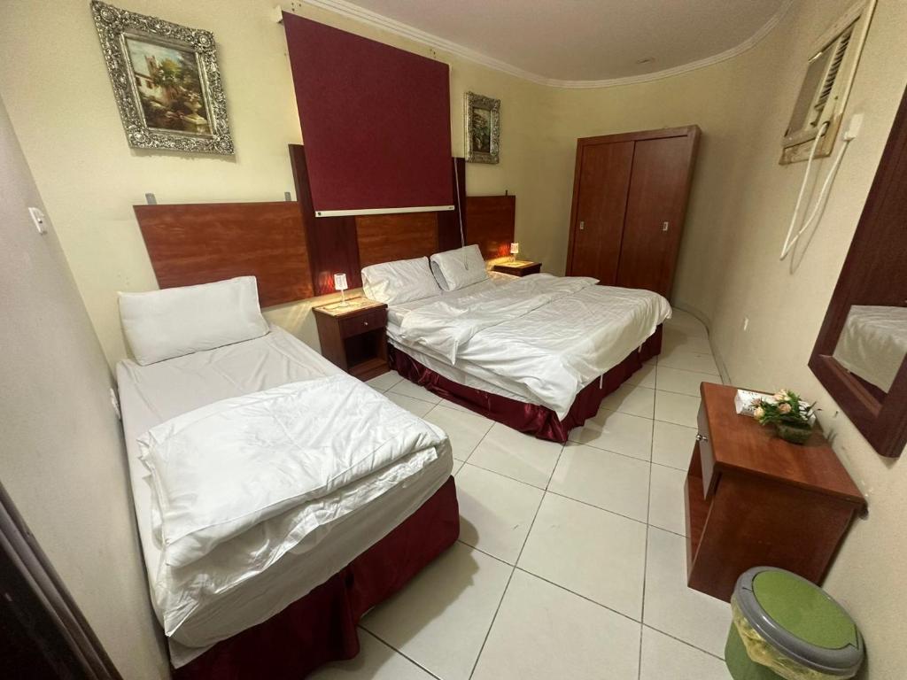 Habitación de hotel con 2 camas y mesa en Nice Suites & Hotels, en La Meca