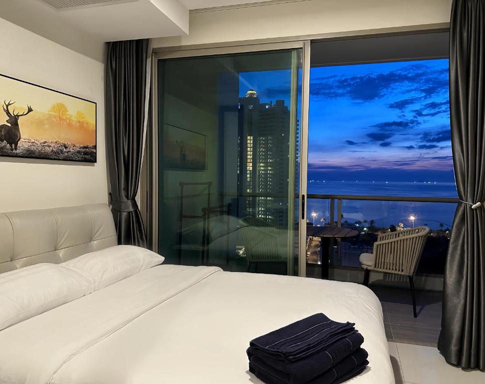 パタヤ・サウスにある芭提雅高层海景奢华公寓The Riviera Jomtien生香家直达海滩 售空のベッドと大きな窓が備わるホテルルームです。