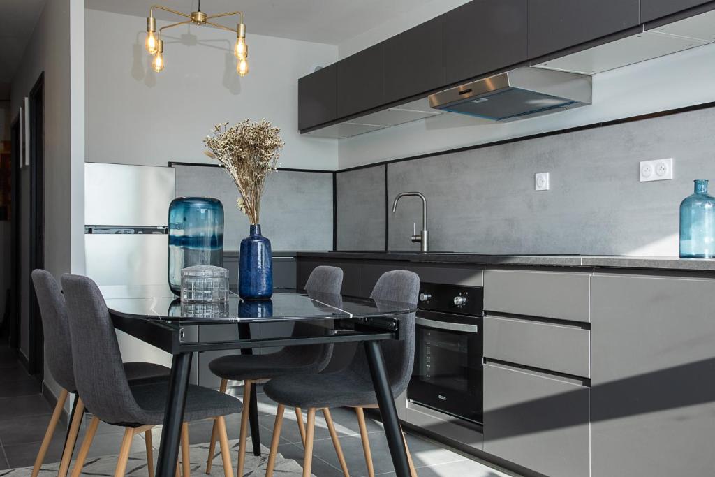 uma cozinha com uma mesa preta e cadeiras em Appartement neuf moderne à louer em Ferney-Voltaire