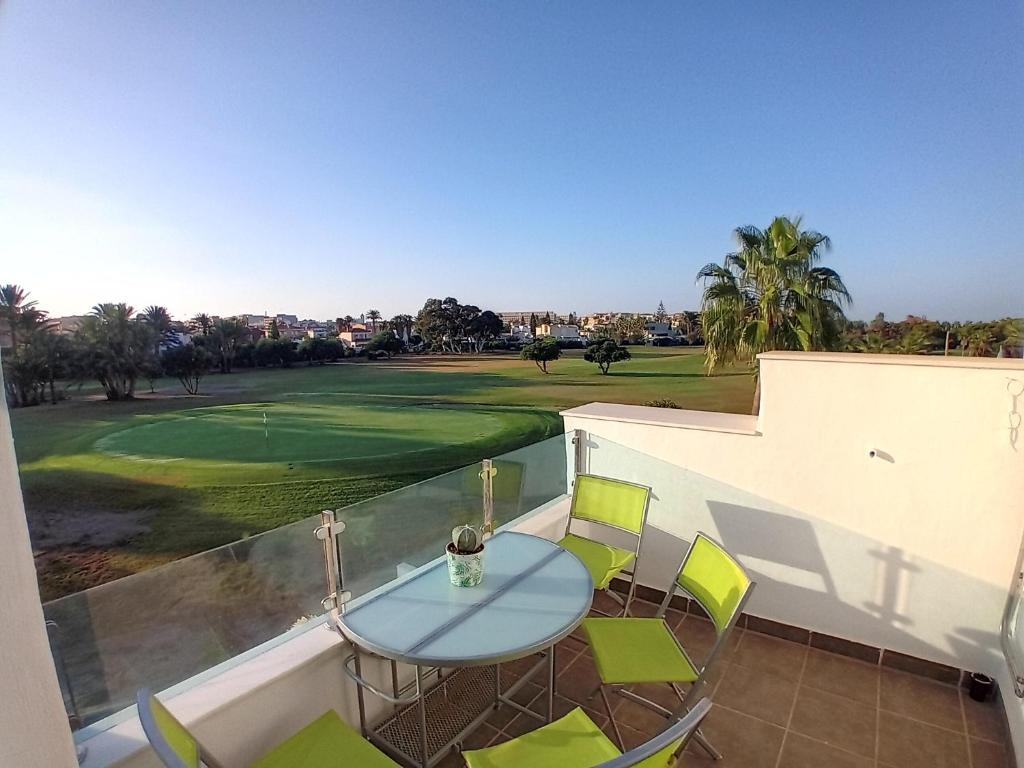 a balcony with a table and chairs and a golf course at La Perla Azul - Terraza panorámica al Sol in Roquetas de Mar