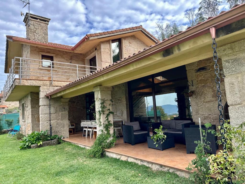 ein Steinhaus mit einer möblierten Terrasse in der Unterkunft Casa O Corvo, chalet cerca de Vigo en plena naturaleza 