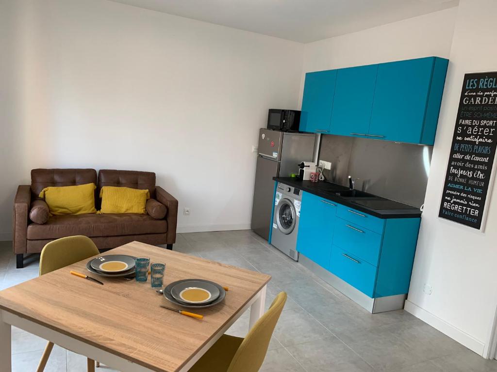 une cuisine et une salle à manger avec une table et des armoires bleues dans l'établissement Room in Toulouse - T2 Toulouse Saint Martin du Touch, à Toulouse