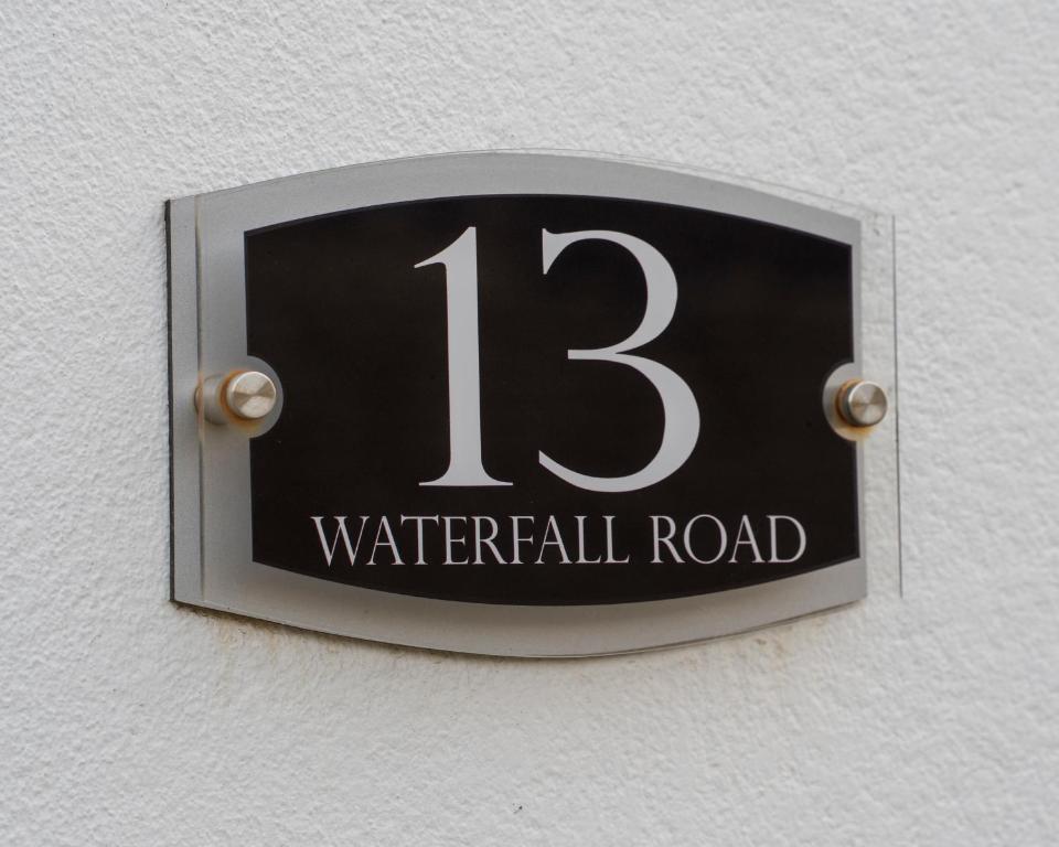 un cartello su un muro che legge la strada ad elica di Waterfall Cottage a Carnlough