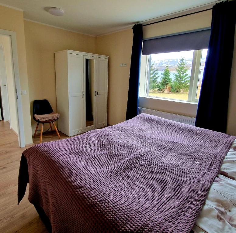 sypialnia z łóżkiem i dużym oknem w obiekcie Olga Apartments w mieście Grundarfjordur