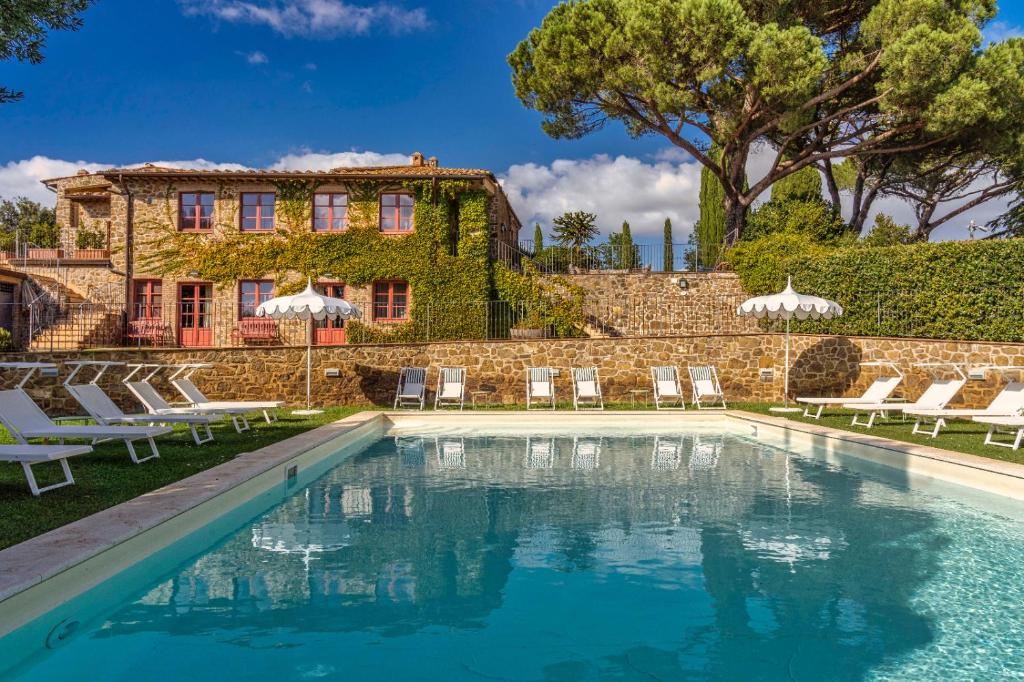una piscina frente a una casa con sillas y un edificio en Le Ragnaie en Montalcino