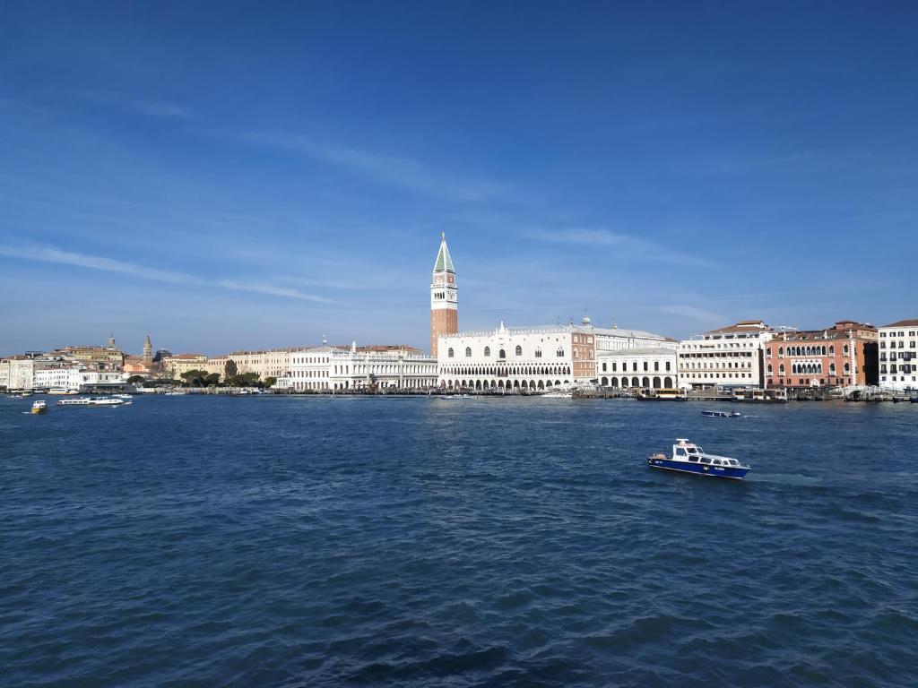 a small boat in the water in front of a city at Favorita Apartments Venezia in Venice-Lido