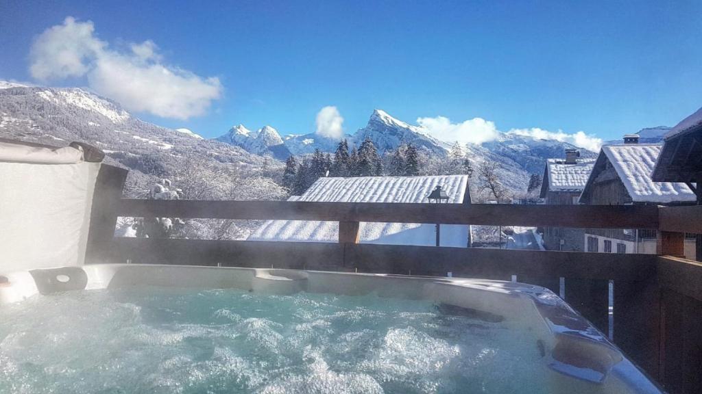 a hot tub on a balcony with a view of mountains at Chalet Pomet in Morillon