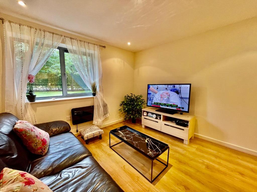 a living room with a couch and a flat screen tv at Cosy apartment in West London in London