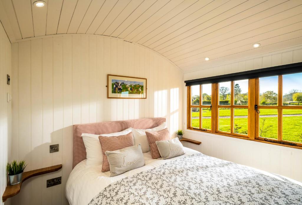 a bedroom with a large bed and windows at The Shepherds Retreat - Ockeridge Rural Retreats in Wichenford
