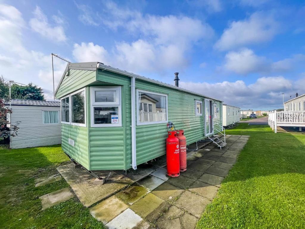 a green house with a fire hydrant next to it at Homely Dog Friendly Caravan At California Cliffs Holiday Park, Ref 50024j in Great Yarmouth