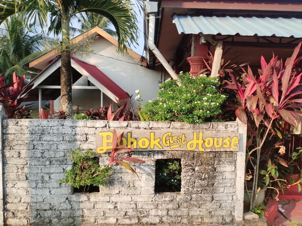 una pared de ladrillo con un cartel delante de un hostal en Bohok Guesthouse, en Pantai Cenang