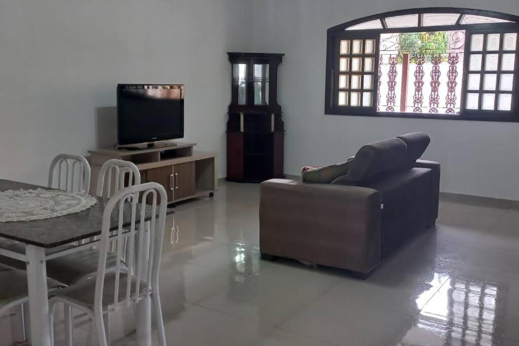 een woonkamer met een bank, een tafel en een televisie bij Casa Temporada em Aparecida com vista para Basílica in Aparecida