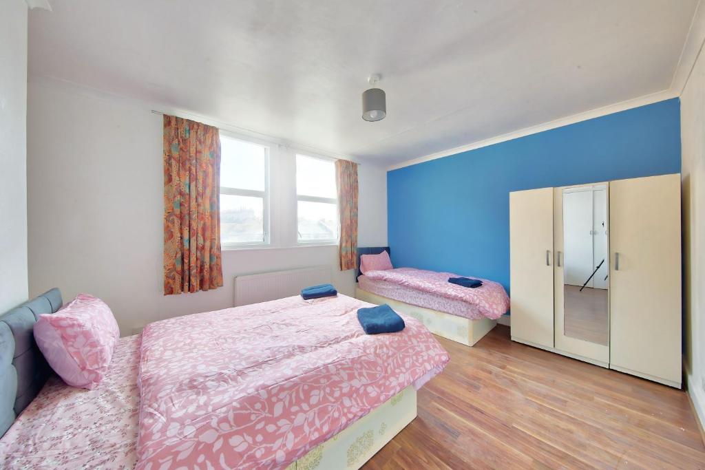 een slaapkamer met 2 bedden en een groot raam bij Cozy London Flat in Londen