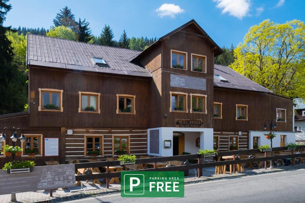 a large wooden building with a sign in front of it at Hotel Hvezda in Pec pod Sněžkou