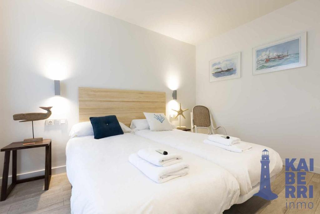 1 dormitorio con 1 cama blanca grande y toallas. en Almiñe by Kaiberri Inmo, en Hondarribia