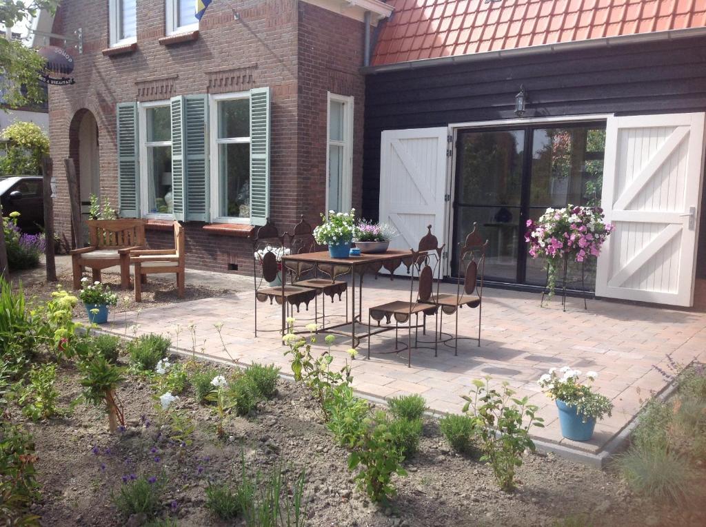 um pátio com uma mesa e cadeiras em frente a uma casa em Sonop em Oostkapelle