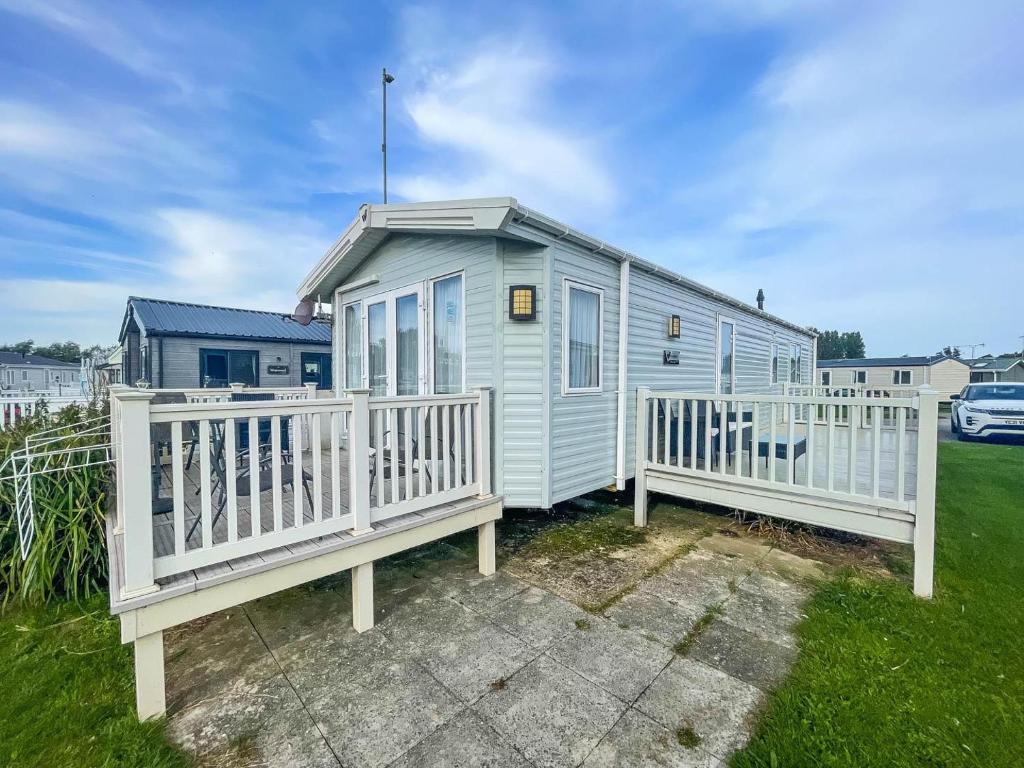 una pequeña casa azul con dos cubiertas blancas en Stunning Dog Friendly Caravan At Manor Park, Hunstanton In Norfolk Ref 23188k, en Hunstanton