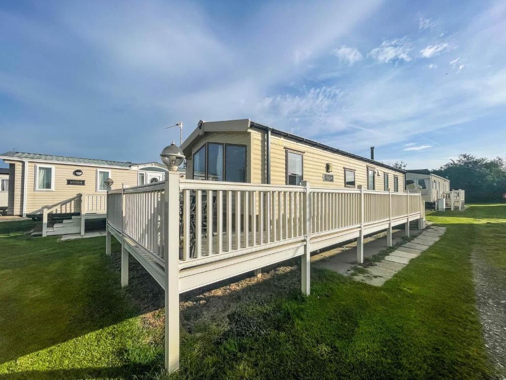a house with a wooden deck and a fence at Caravan With Decking Within Walking Distance To Hunstanton Beach Ref 23054s in Hunstanton