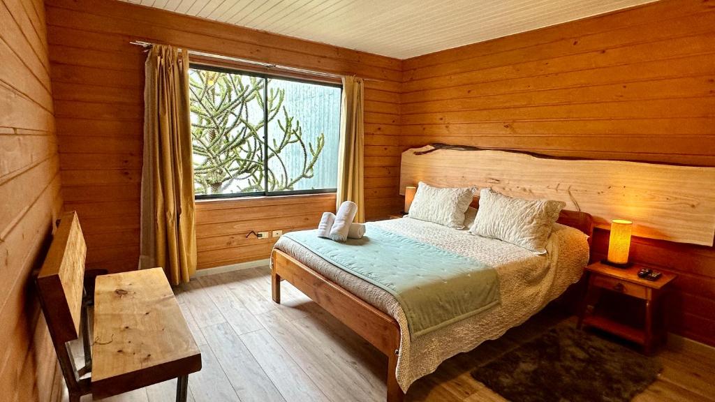 1 dormitorio con 1 cama en una habitación de madera con ventana en Hotel El Coihue, en Pucón