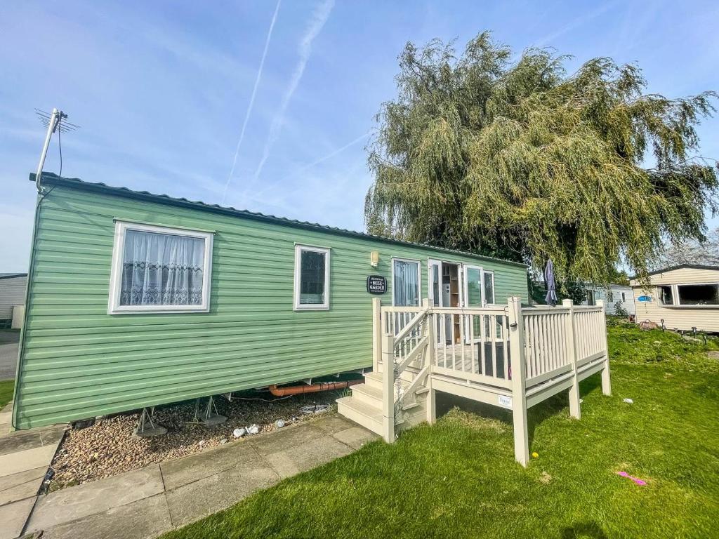 a green tiny house with a wooden porch at Lovely Dog Friendly Caravan At Southview Holiday Park In Skegness Ref 33053s in Skegness
