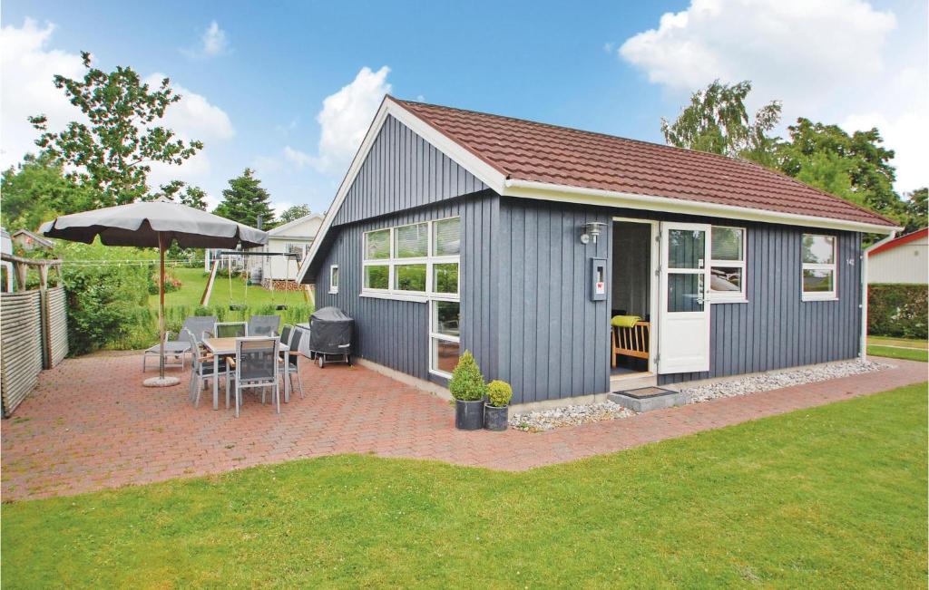 a grey shed with a table and chairs and an umbrella at Stunning Home In Haderslev With Kitchen in Kelstrup Strand