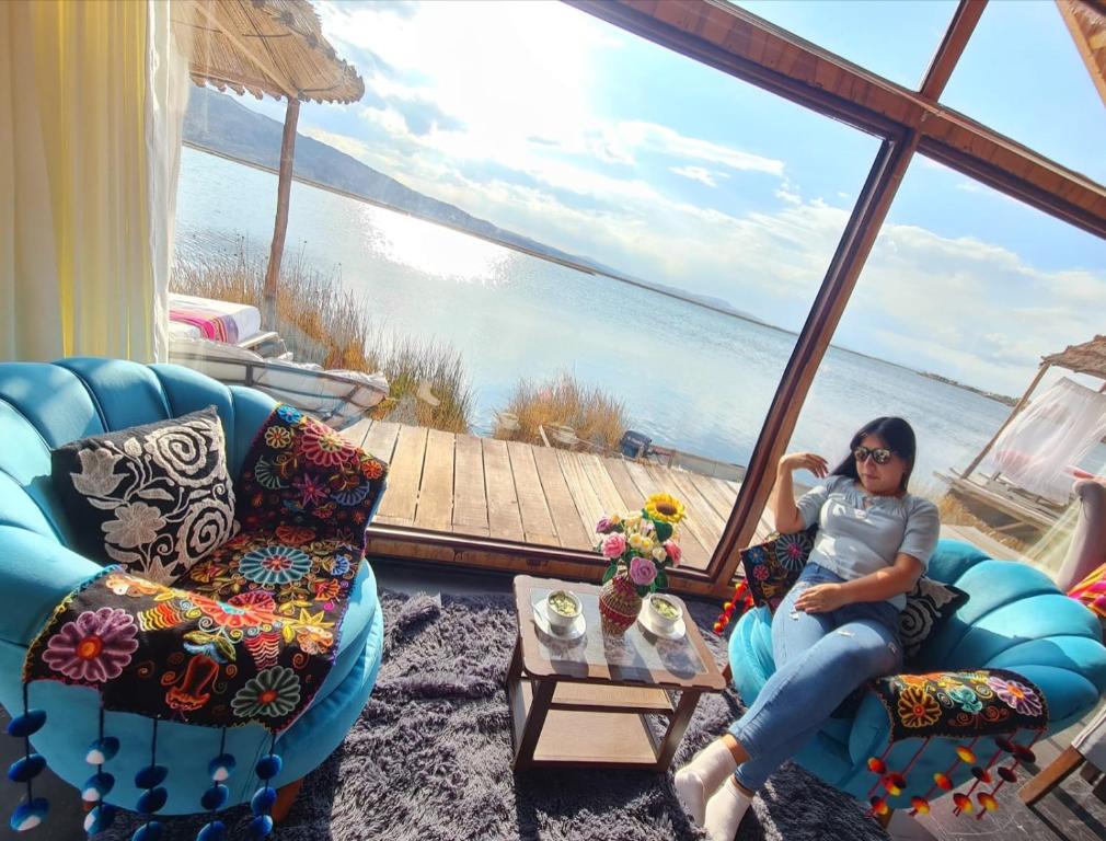 een vrouw in een stoel in een kamer met uitzicht op het water bij Uros Walysuma Titicaca Lodge in Puno