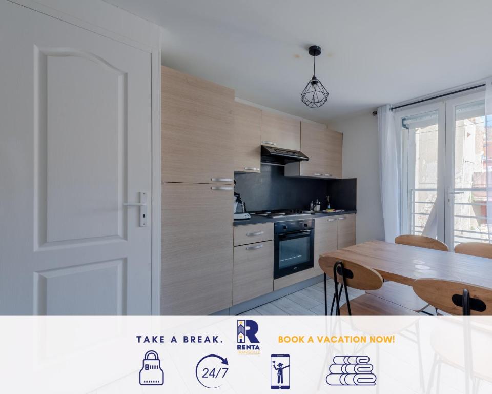 een keuken met een tafel, een koelkast en een deur bij Le Joli - Parking - Near Perpignan in Saleilles