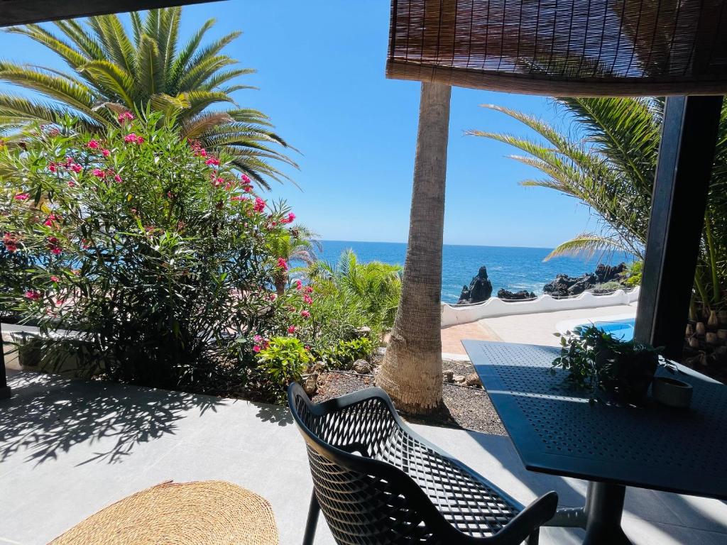 un patio con mesa, sillas y el océano en Ocean shore apartment 2, en Puerto de Santiago