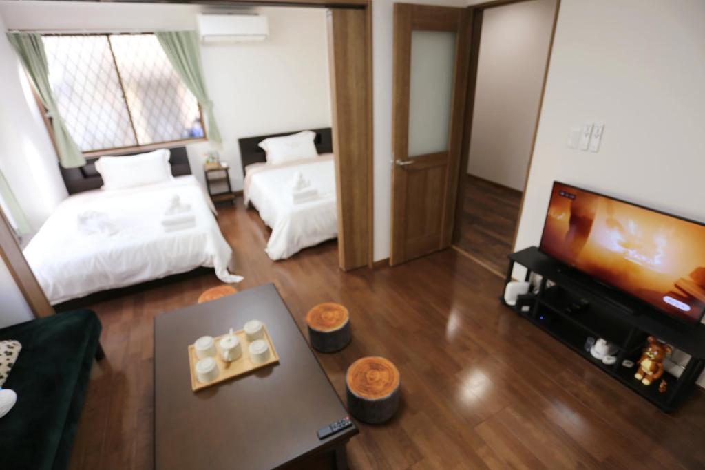 sala de estar con 2 camas y TV de pantalla plana en Kita 2 Storey Homestay, en Tokio