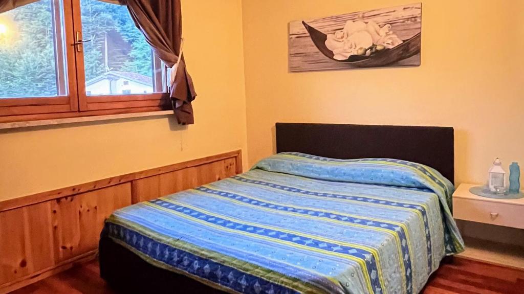 una camera da letto con un letto con un piumone blu e una finestra di Brain Residence Laceno a Villaggio Laceno
