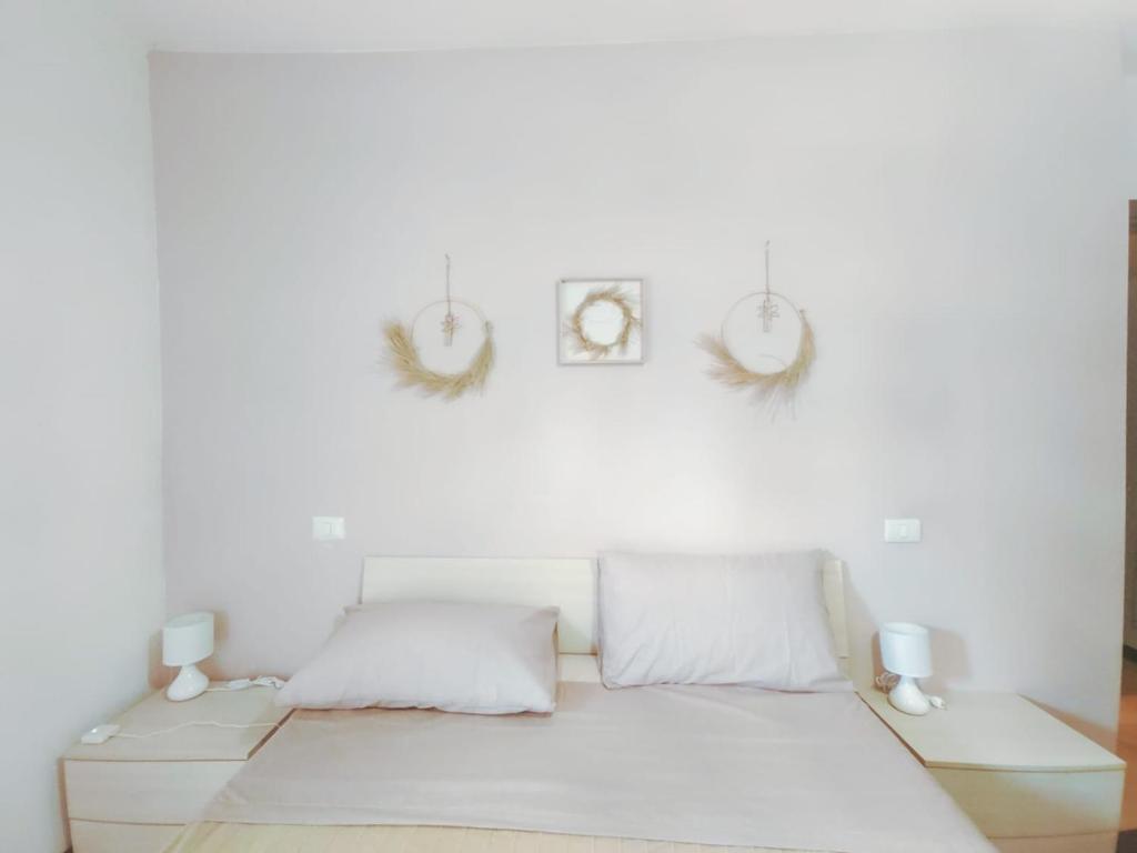 a white bedroom with a bed with two lamps at Casa Elia in Reggio Emilia