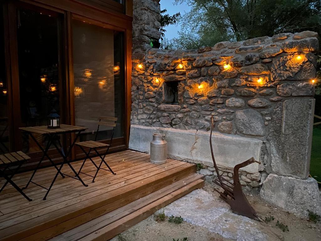eine hölzerne Veranda mit einer Steinmauer mit Beleuchtung in der Unterkunft Turisme Rural Ca l'Axai casa 3 in Pi