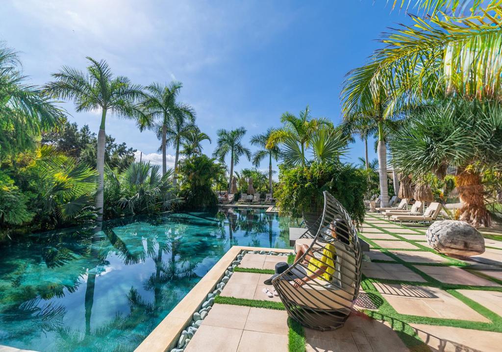 a hammock sitting next to a swimming pool with palm trees at Royal River, Luxury Hotel - Adults Only in Adeje